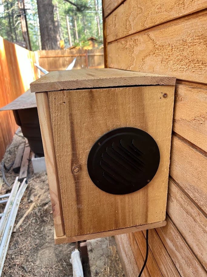 Front view of the finished wood cover on the sauna wall with a louvered vent grill