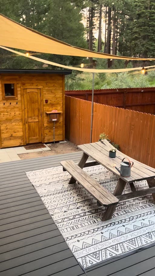 Outdoor sauna on a backyard deck with picnic table, shade sail, and string lights in South Lake Tahoe