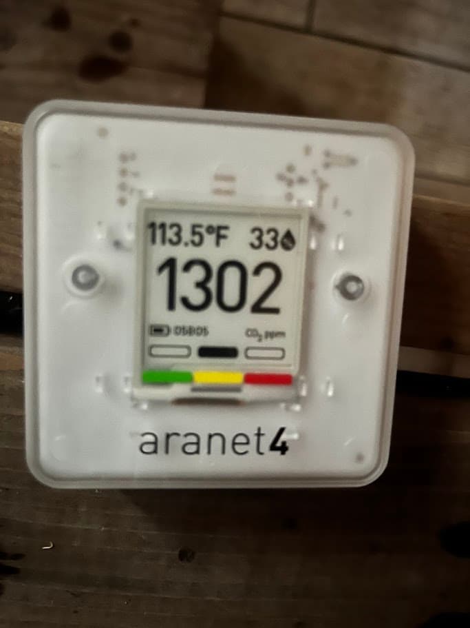 A CO2 monitor inside a sauna reading 1302 ppm at 113°F, before the exhaust fan is switched on