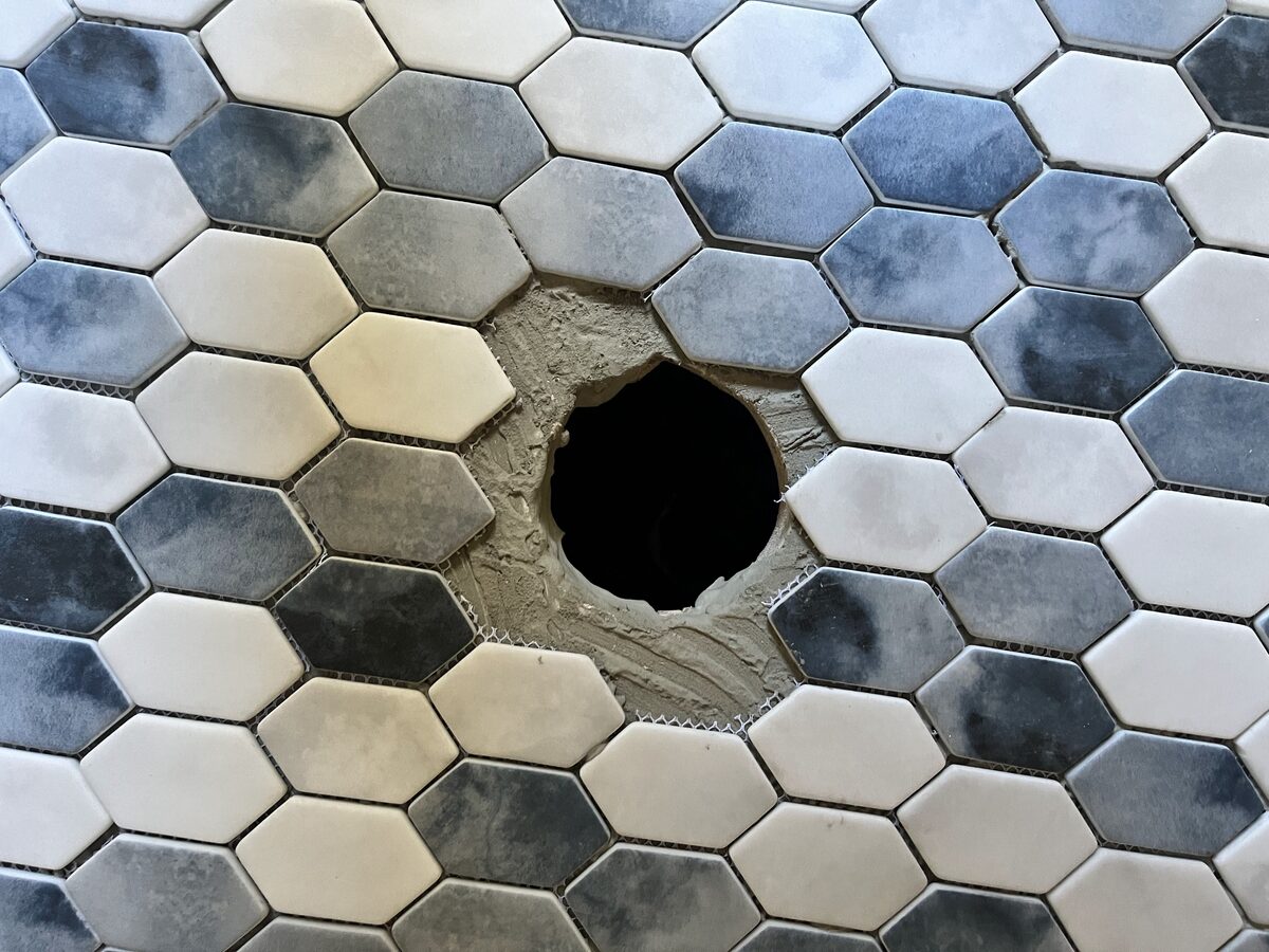 Close-up of the drain opening tiled in — the surrounding floor pitches to this low point