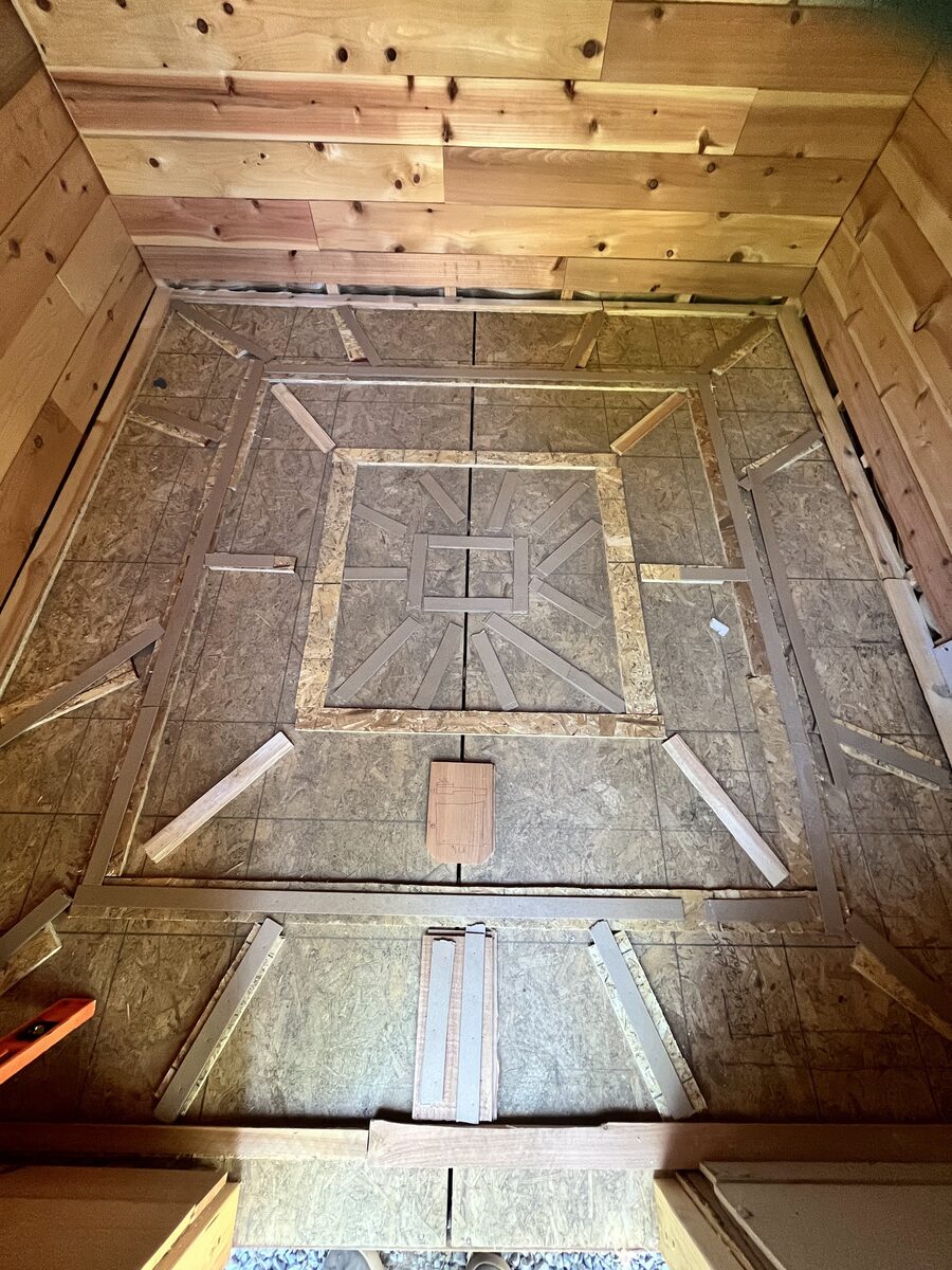 Tapered wood sleepers pitching the subfloor toward the center drain before tiling