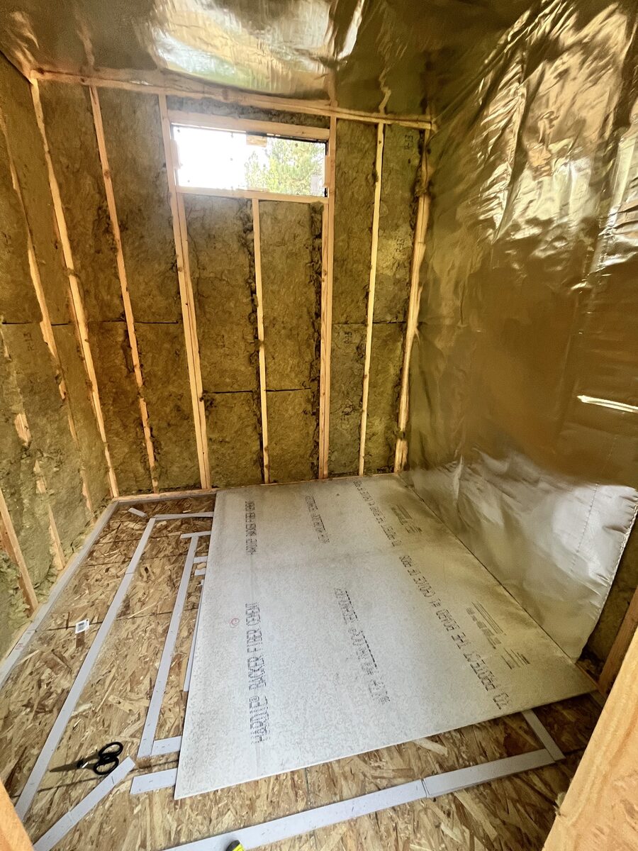 Building up the sauna floor over insulated, foil-sealed framing with the drain lines run and backer board going down