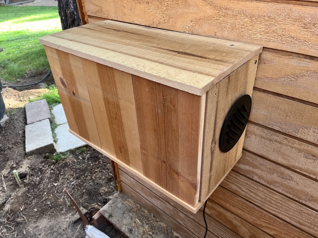 Finished wood cover mounted on the exterior sauna wall with the vent grill installed