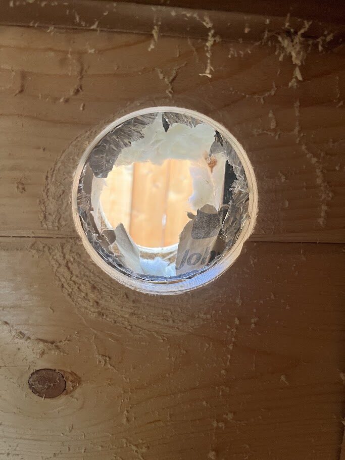 A clean, finished 4-inch vent hole cut through the sauna wall
