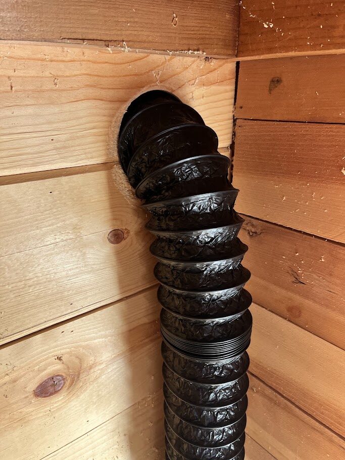 Insulated ventilation ducting run through the wall opening and down the sauna corner
